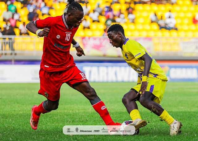 "Soccer players competing during a match, wearing red and yellow jerseys."