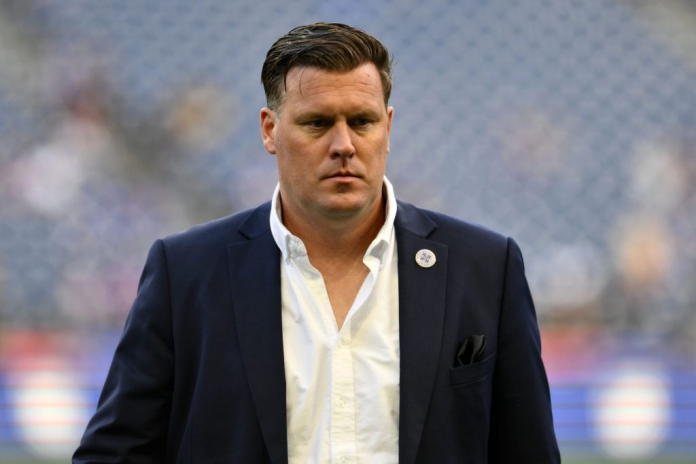 A focused football coach walking on the field during a match. A focused football coach walking on the field during a match.