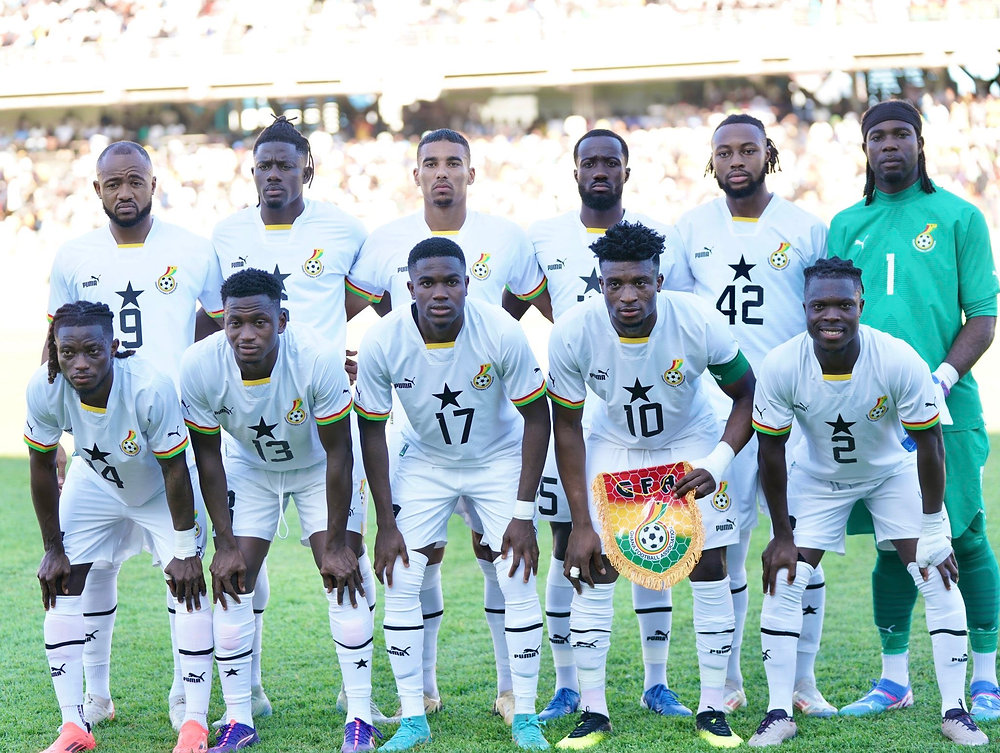 "National soccer team posing for a group photo in white jerseys."