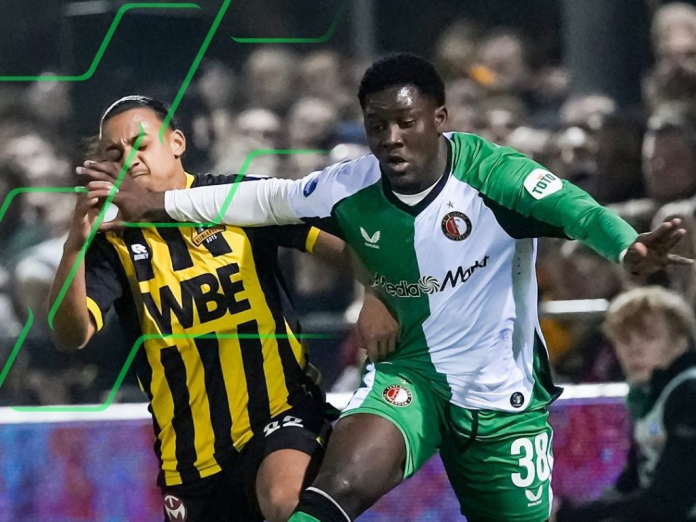 "Football player in green and white jersey battling for the ball during a match."