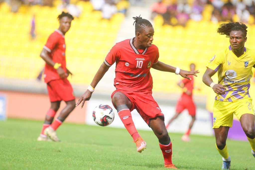 "Soccer player in red jersey controlling the ball during a match."