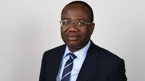 "Kwesi Nyantakyi wearing glasses and a dark suit with a striped tie, posing for a portrait."