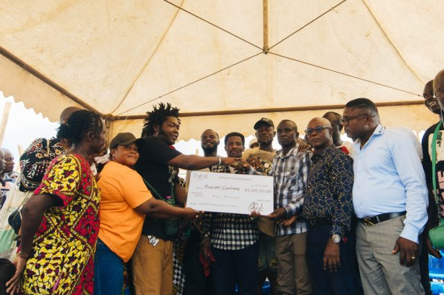 Community members presenting a symbolic cheque to support Kantamanto Market fire victims