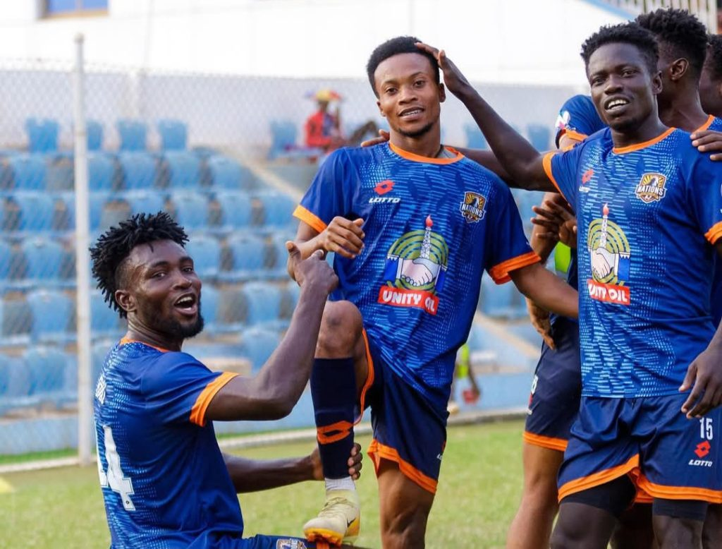 Vision FC players in blue and orange jerseys celebrating a goal on the field, showcasing camaraderie and excitement during a match.