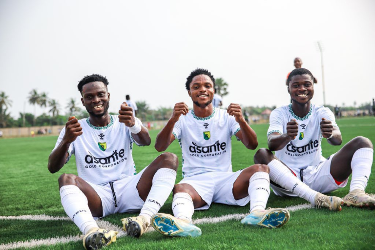 players in white jerseys celebrating a goal on the field, showcasing camaraderie and excitement during a match.