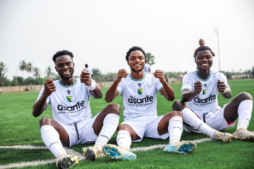 players in white jerseys celebrating a goal on the field, showcasing camaraderie and excitement during a match.