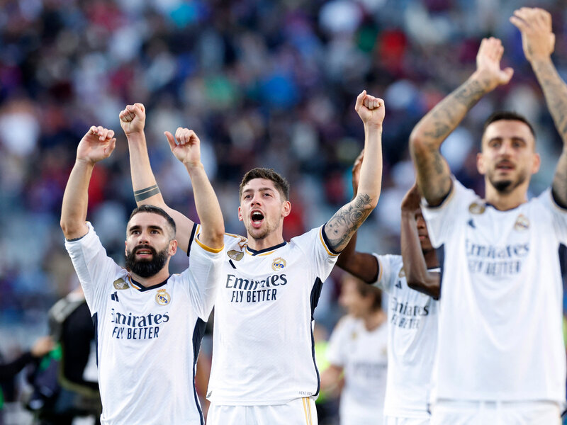 "Real Madrid players celebrating on the field with raised arms."