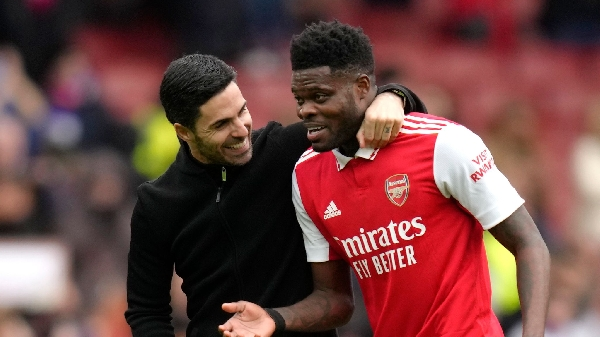 "Arsenal manager Mikel Arteta shares a light moment with player Thomas Partey on the field."