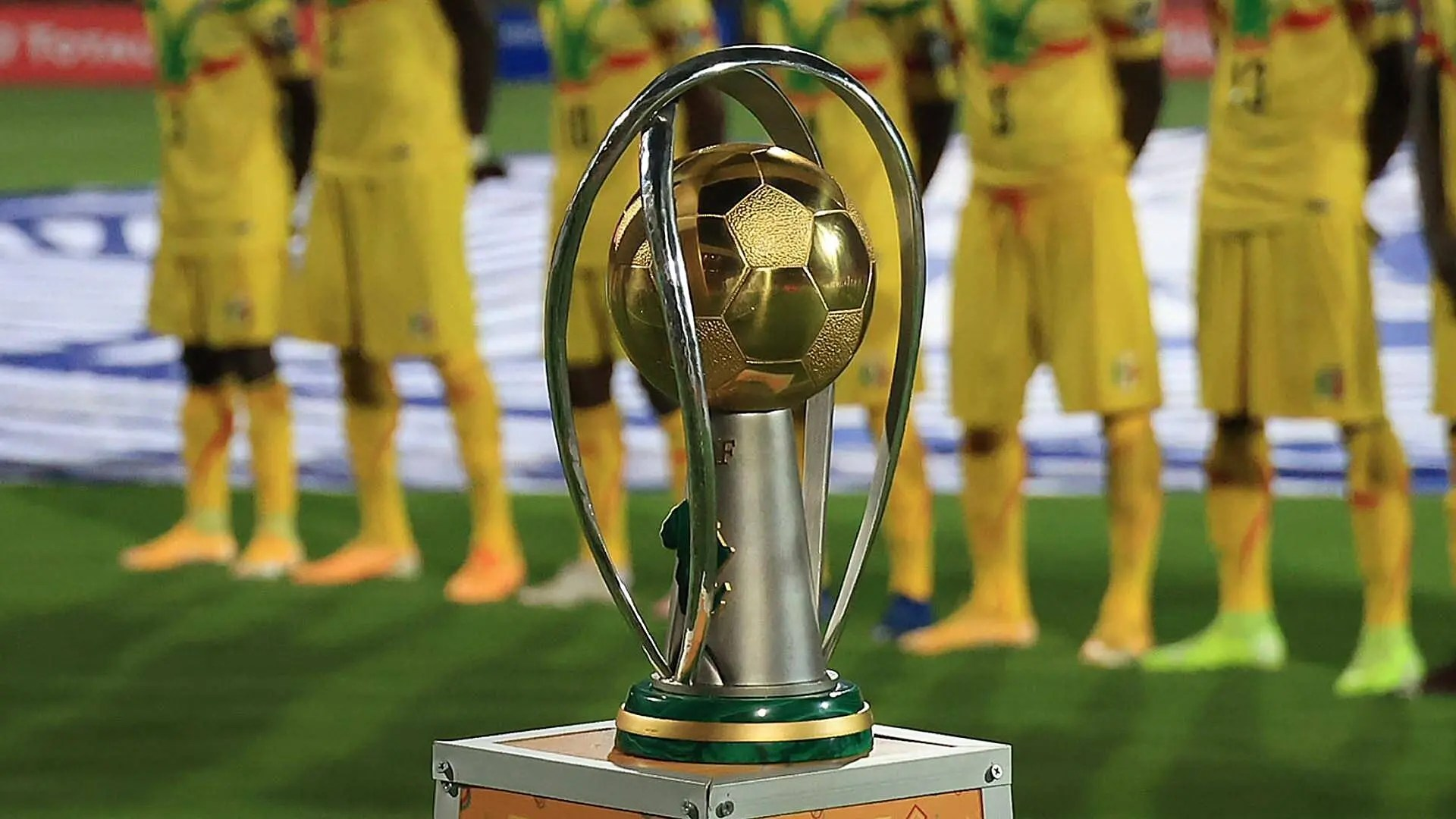 "Soccer trophy displayed in front of players in yellow jerseys."