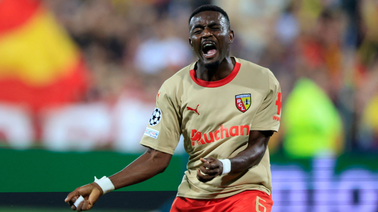 A football player in a beige jersey celebrating intensely during a match.