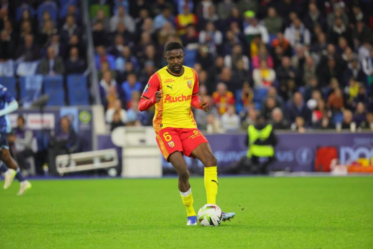A football player in a yellow and red striped jersey sprinting on the field during a match.