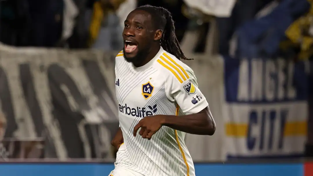 Football player in a white LA Galaxy jersey celebrating.