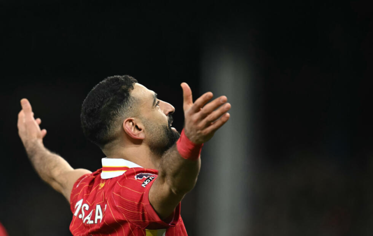 A football player in a red jersey celebrating with arms raised.
