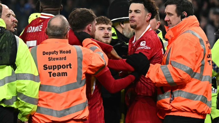 A football player in a red jersey celebrating with arms raised.