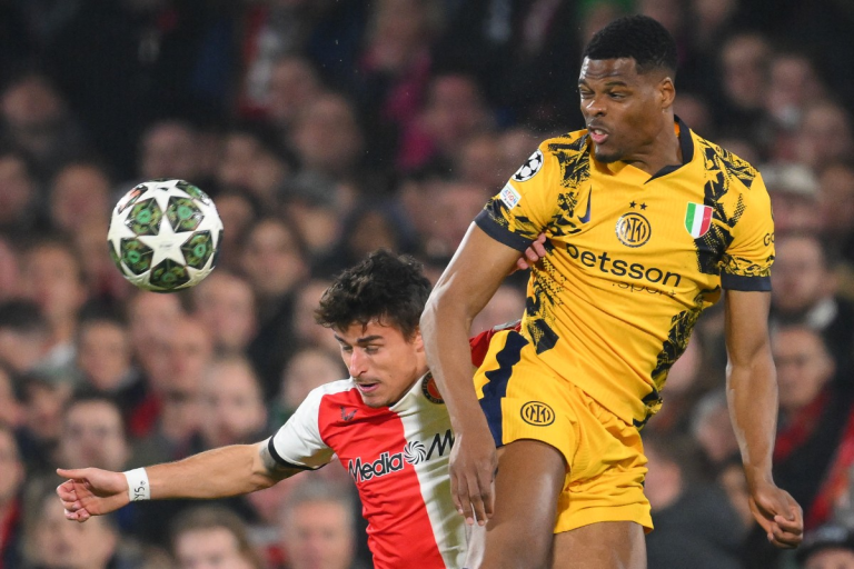 An Inter Milan player in a yellow jersey competes for the ball against a Feyenoord player.