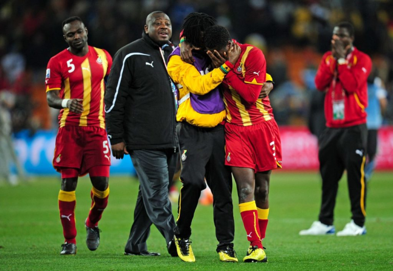 Ghanaian football players consoling each other on the field after a match.