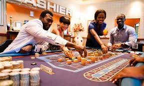 Group of people playing at a casino table with chips and drinks.