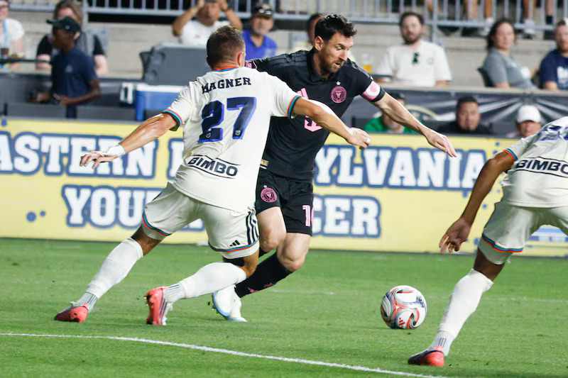 Mchezaji wa Inter Miami Lionel Messi mwenye jezi nyeusi akidhibiti mpira huku akidhibitiwa na Kai Wagner wa Philadelphia Union.