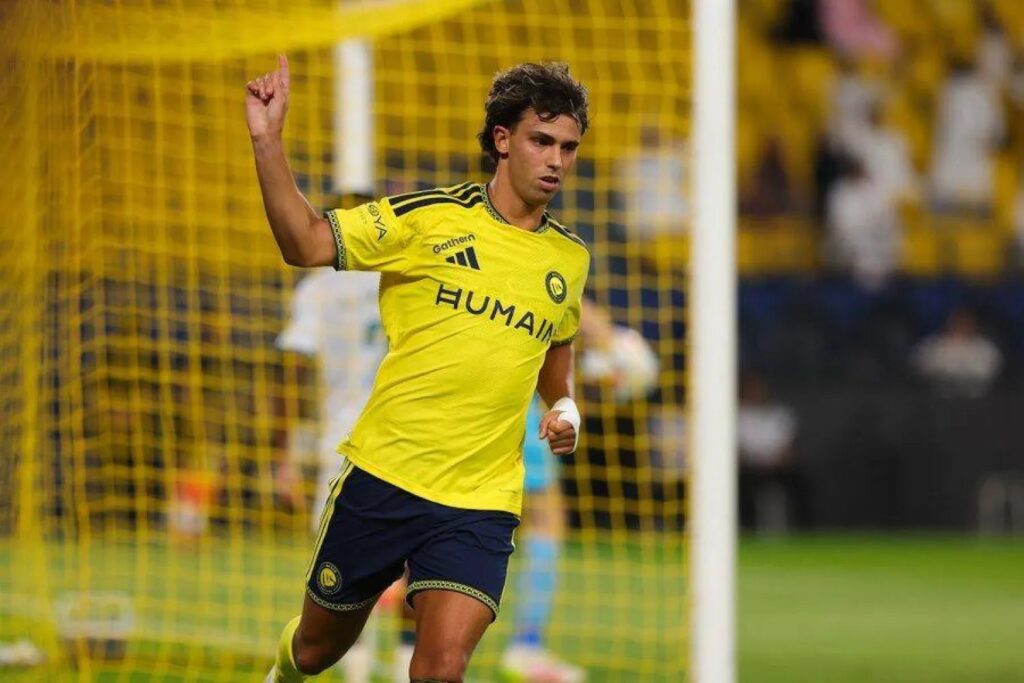 joao-felix-ashangilia-goli-al-nassr Mchezaji mpira João Félix aliyevalia jezi ya njano akiwa ameinua kidole chake juu kushangilia karibu na wavu wa goli.