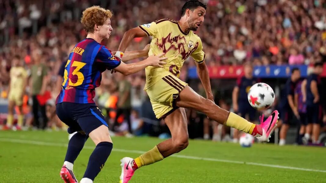 Mchezaji wa Al Ahly akipiga mpira huku akihimili shinikizo kutoka kwa mchezaji wa Barcelona.