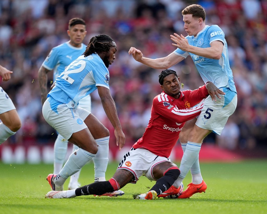 Wachezaji wa Manchester City na Manchester United wakigombea mpira kwa ukaribu wa hali ya juu uwanjani.