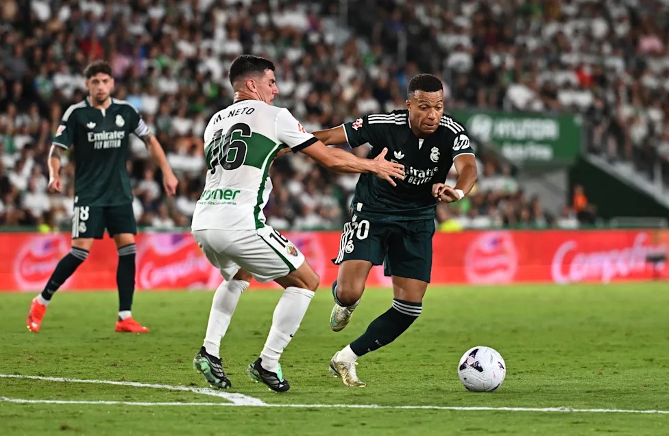 Mapambano ya Mpira Kati ya Wachezaji wa Elche na Real Madrid Mchezaji wa Real Madrid akimiliki mpira huku akizuiliwa na beki wa Elche katika uwanja wa Manispaa ya Martinez Valero