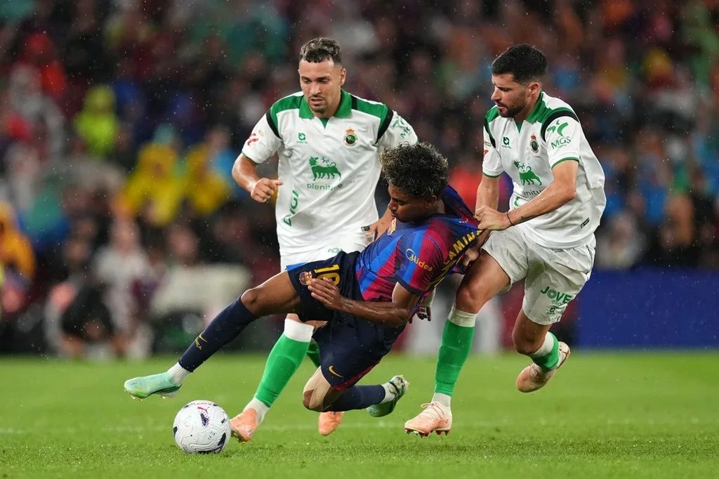lamine-yamal-akipambana-na-mabeki-barcelona-vs-racing-santander Mchezaji wa FC Barcelona Lamine Yamal akipambana na mabeki wawili wa Racing Santander kupata mpira wakati wa mechi.