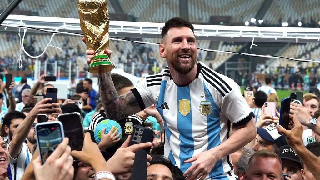 Lionel Messi akiwa ameshikilia kombe juu huku akizungukwa na umati mkubwa wa mashabiki waliomshangilia uwanjani