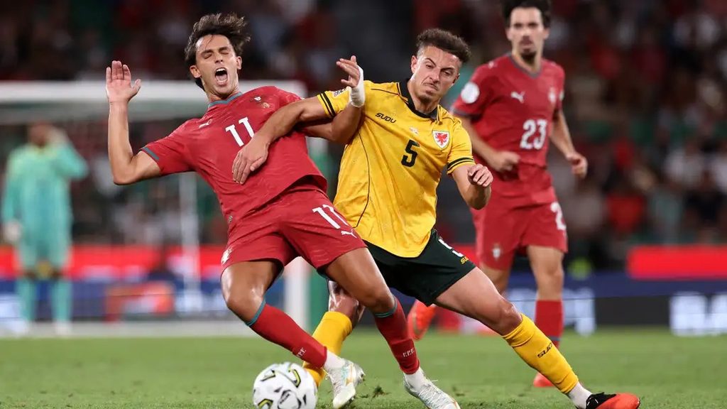 João Félix akipambana na beki wa Wales kuwania mpira João Félix akiwa kwenye mvutano mkali wa kuwania mpira na mchezaji wa Wales aliyevaa jezi ya namba 5
