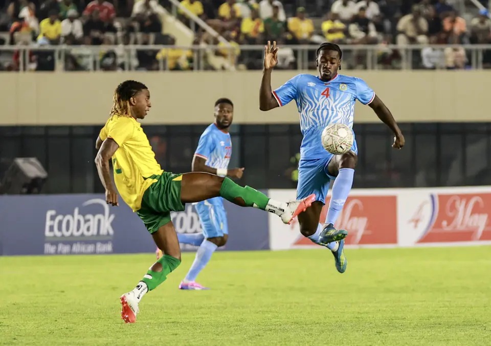 Mapambano ya Kuvutia Kati ya Wachezaji wa DR Congo na Zimbabwe Uwanjani Mchezaji wa DR Congo akipigania mpira hewani dhidi ya mpinzani wake kutoka timu ya taifa ya Zimbabwe wakati wa mechi ya ushindani.