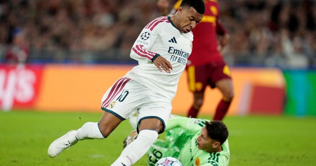 Kylian Mbappé aliyevaa jezi namba 10 ya Real Madrid akimruka mlinda mlango wa Roma aliyekuwa chini na kuingiza mpira nyavuni.