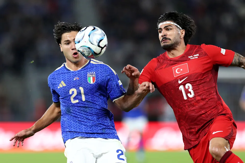 Mchezaji wa Italia mwenye namba 21 akipambana kuwania mpira wa kichwa dhidi ya mchezaji wa Türkiye mwenye namba 13.