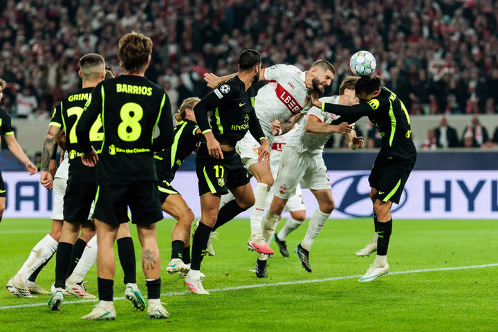 Wachezaji wa Stuttgart na Atletico Madrid wakiruka na kugombea mpira wa kichwa langoni wakati wa mpira wa adhabu au kona.