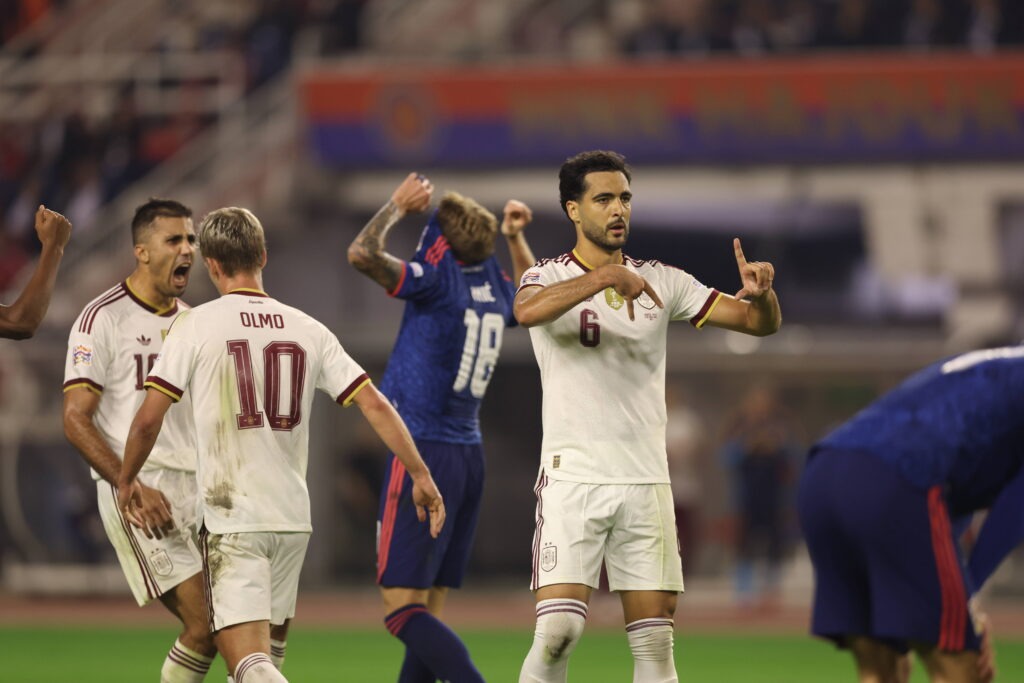 Mikel Merino akiwa amevaa jezi namba 6 ya Spain akionyesha ishara kwa vidole vyake huku wachezaji wenzake wakiwemo Dani Olmo wakishangilia nyuma yake.