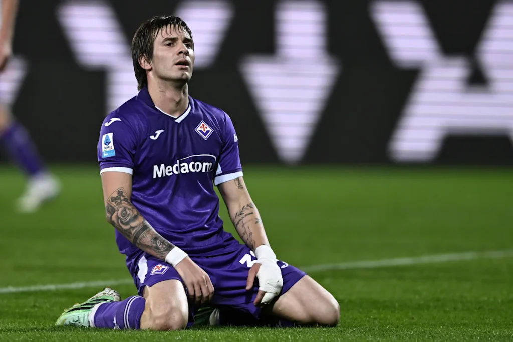 mchezaji-wa-fiorentina-akiwa-amekata-tamaa-uwanjani Mchezaji wa Fiorentina aliyevaa jezi ya zambarau akiwa amekaa uwanjani kwa majonzi baada ya mchezo kuisha kwa sare.