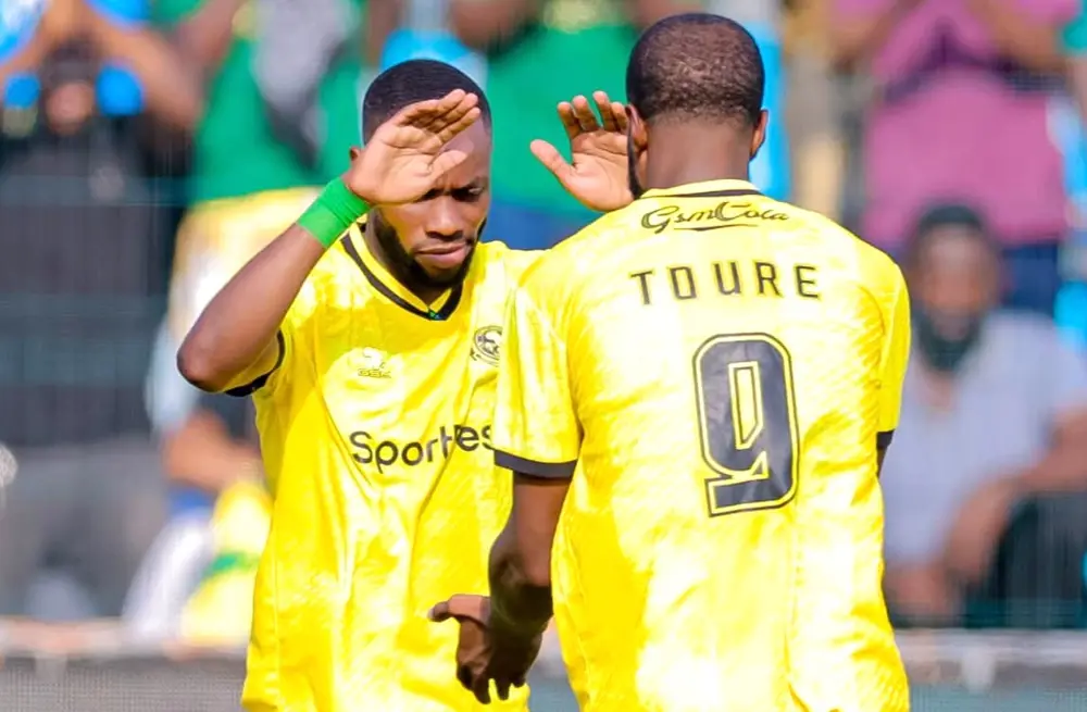 wachezaji-wa-yanga-sc-wakishangilia-uwanjani Wachezaji wa Yanga SC waliovaa jezi za njano wakishangilia kwa kushika paji la uso uwanjani.