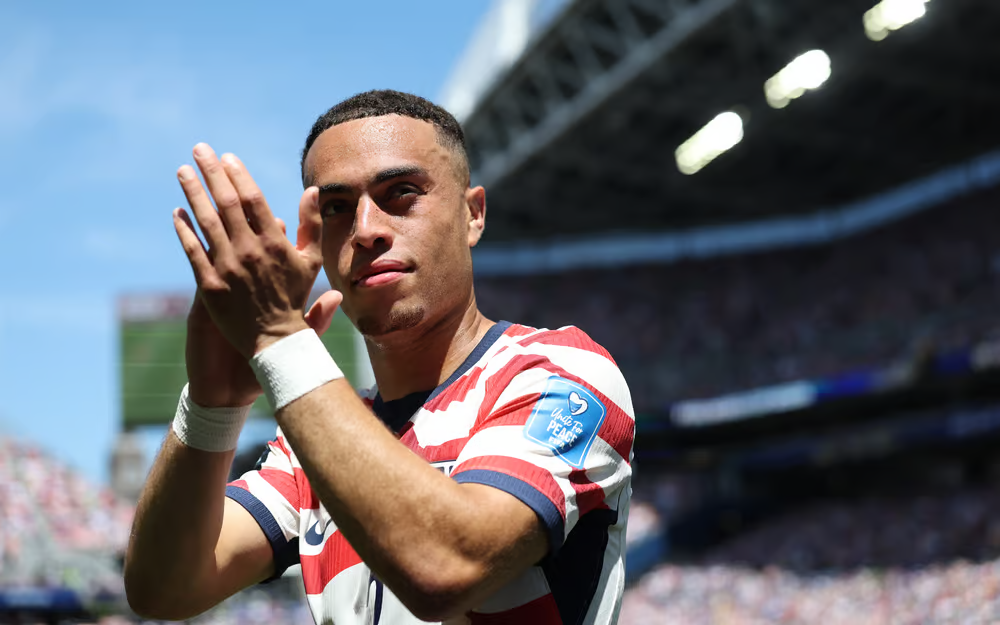 USA football player applauding fans after a match while wearing the national team jersey