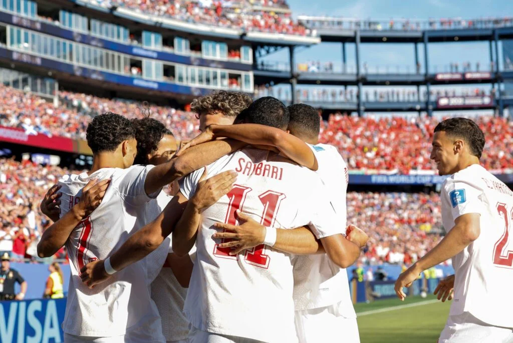 Footballl players celebrate a goal during a FIFA World Cup match in front of cheering fans.