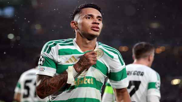 Celtic forward in a green-and-white kit celebrates on the pitch after scoring during a UEFA Champions League football match.