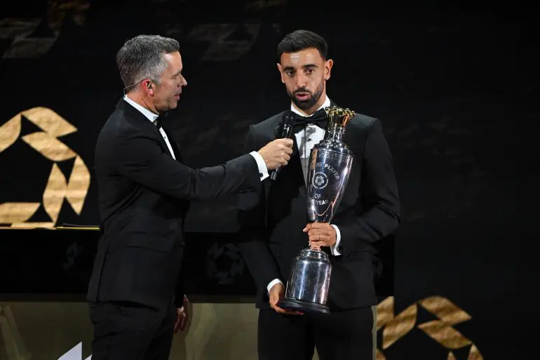 Bruno Fernandes holds the PFA Players’ Player of the Year trophy on stage after receiving the award at the 2026 PFA Awards.