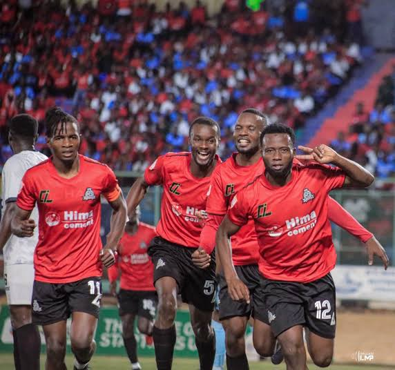 Four Vipers SC players in red shirts run together in celebration in front of a crowded stand.