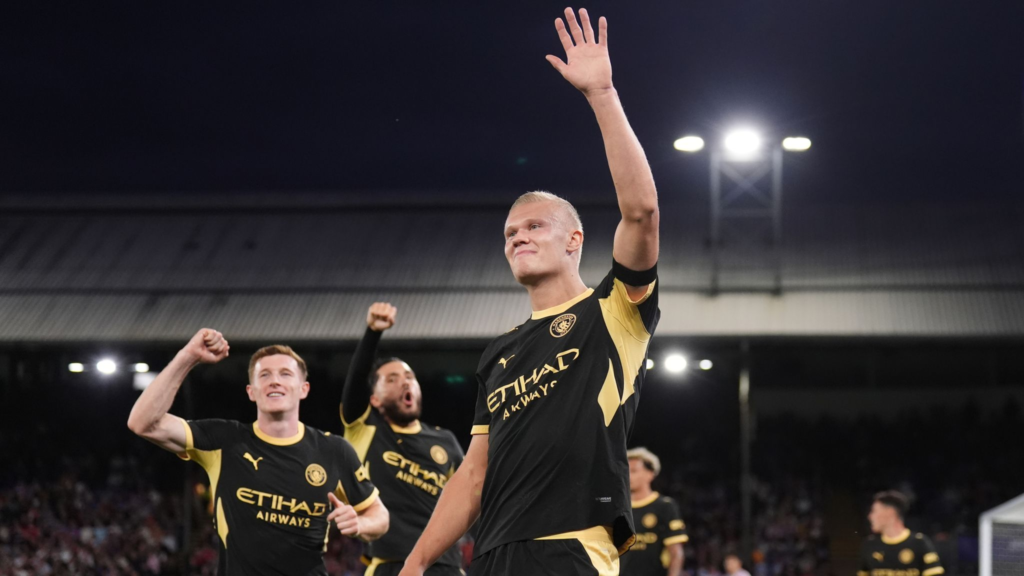 Erling Haaland raises his hand while celebrating with Manchester City teammates after scoring against Crystal Palace.