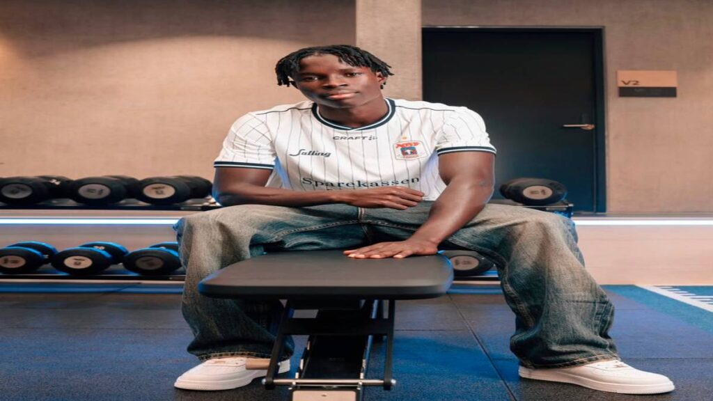 Elvis Torach sits in a gym wearing an AGF Aarhus shirt following his transfer from El Cambio Academy.
