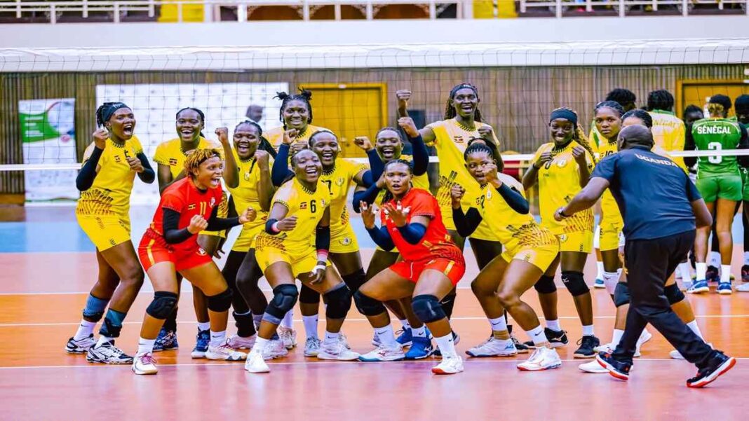 Uganda Lady Volleyball Cranes players in yellow and red kits celebrate together on the court after a successful match at the African Nations Championship.