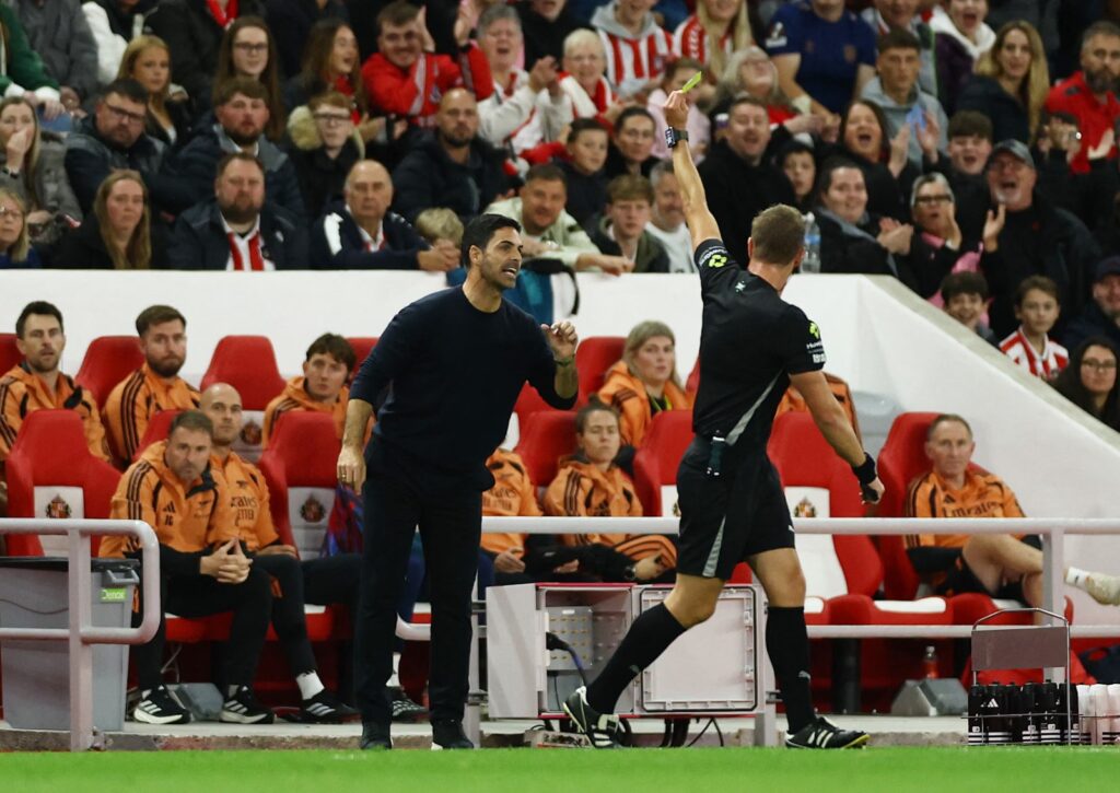 Referee John Brooks shows a yellow card to Arsenal manager Mikel Arteta for leaving his technical area.