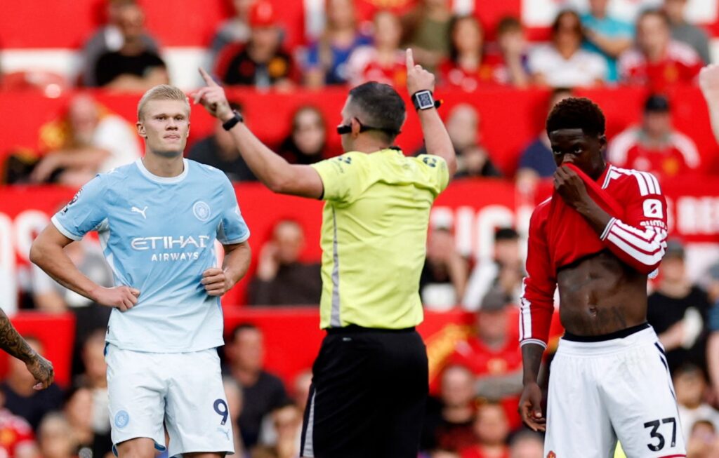 Referee Michael Oliver signals to award the opening goal after consulting VAR.