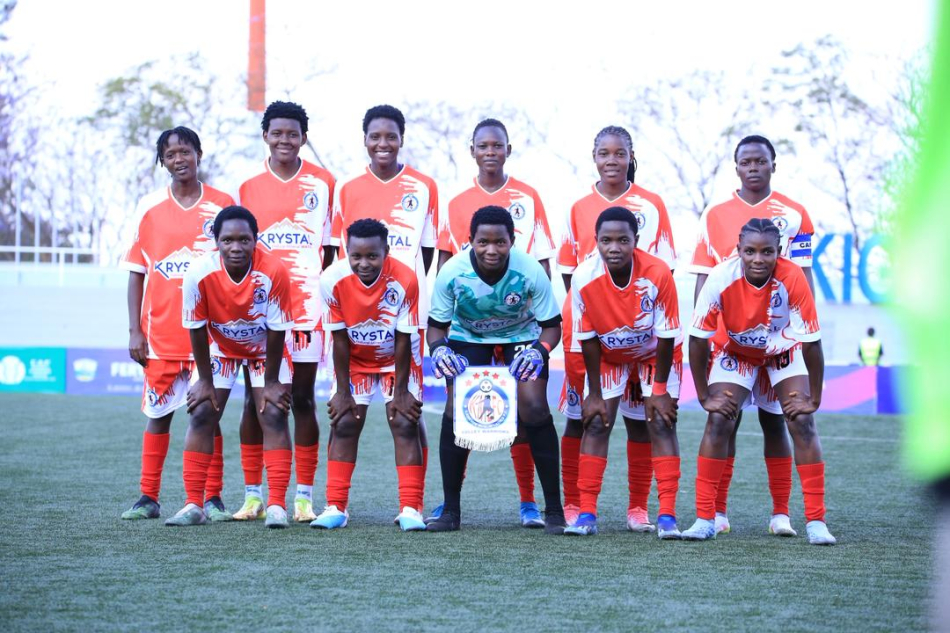 Eleven Kawempe Muslim players in red-and-white kits pose together on the football pitch.