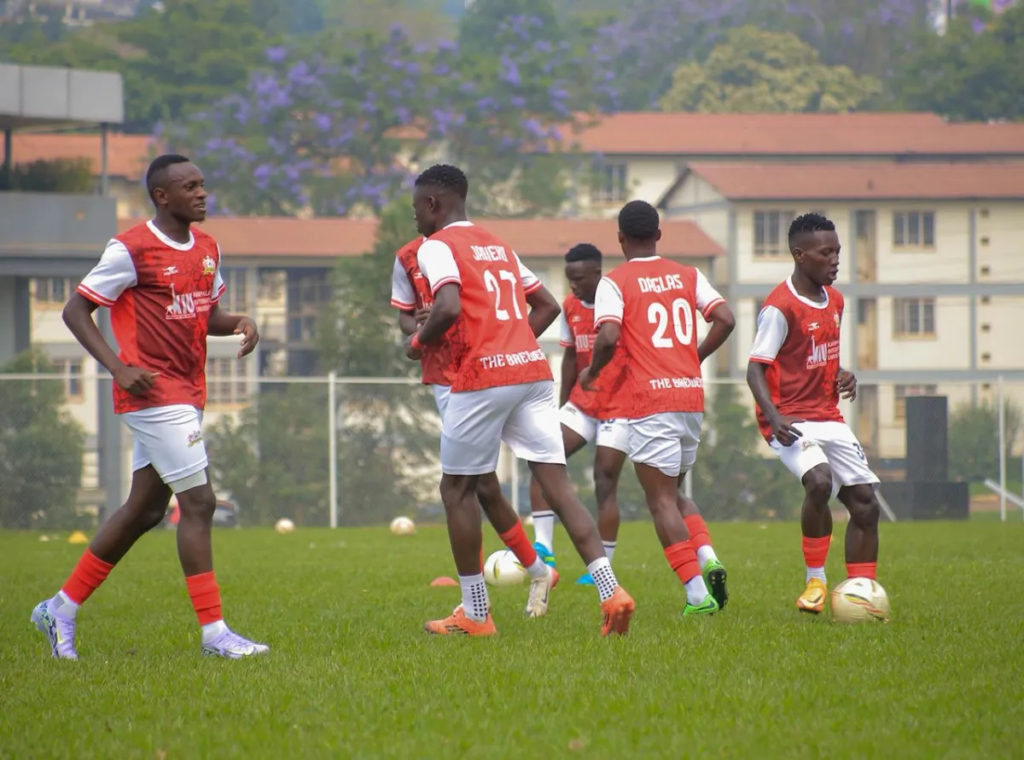 Ntugasaze players in red-and-white kits performing ball-work drills on a grass pitch.