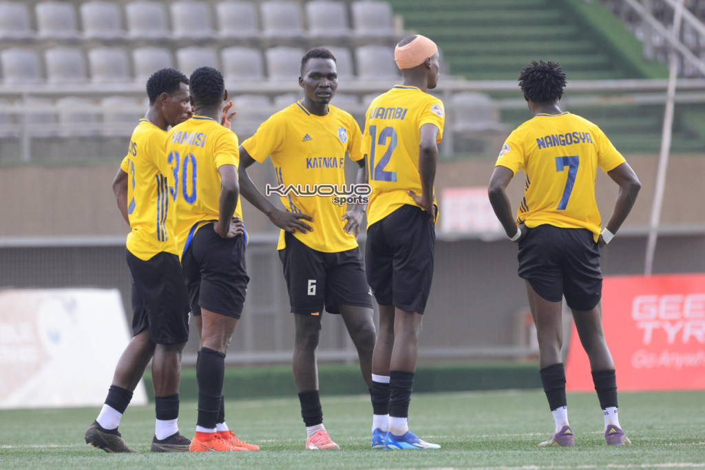 Kataka players Wamisi, Wambi and Nangosya stand with teammates in yellow shirts on the pitch.