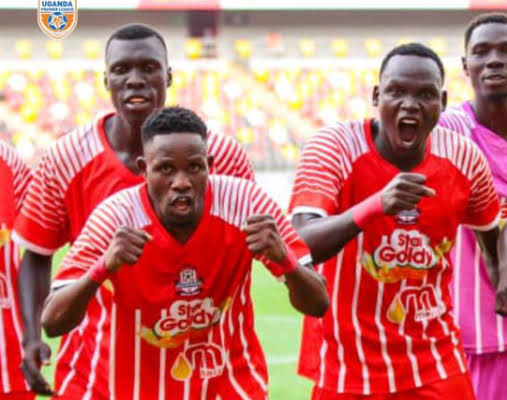 Blacks Power players in red jerseys celebrate with raised fists on the pitch.